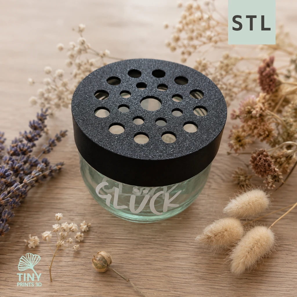 STL-Datei: Blumenretter mit Lochmuster für das Glücksglas Kleine Stiche Blumenretter mit Lochmuster auf einem Glücksglas, dekoriert mit Trockenblumen auf einem Holztisch. STL-Datei